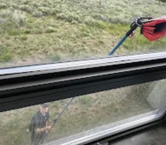 Water-fed brush cleaning a window above a hillside