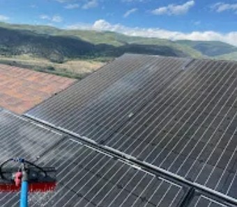 Brush cleaning solar panels on a roof
