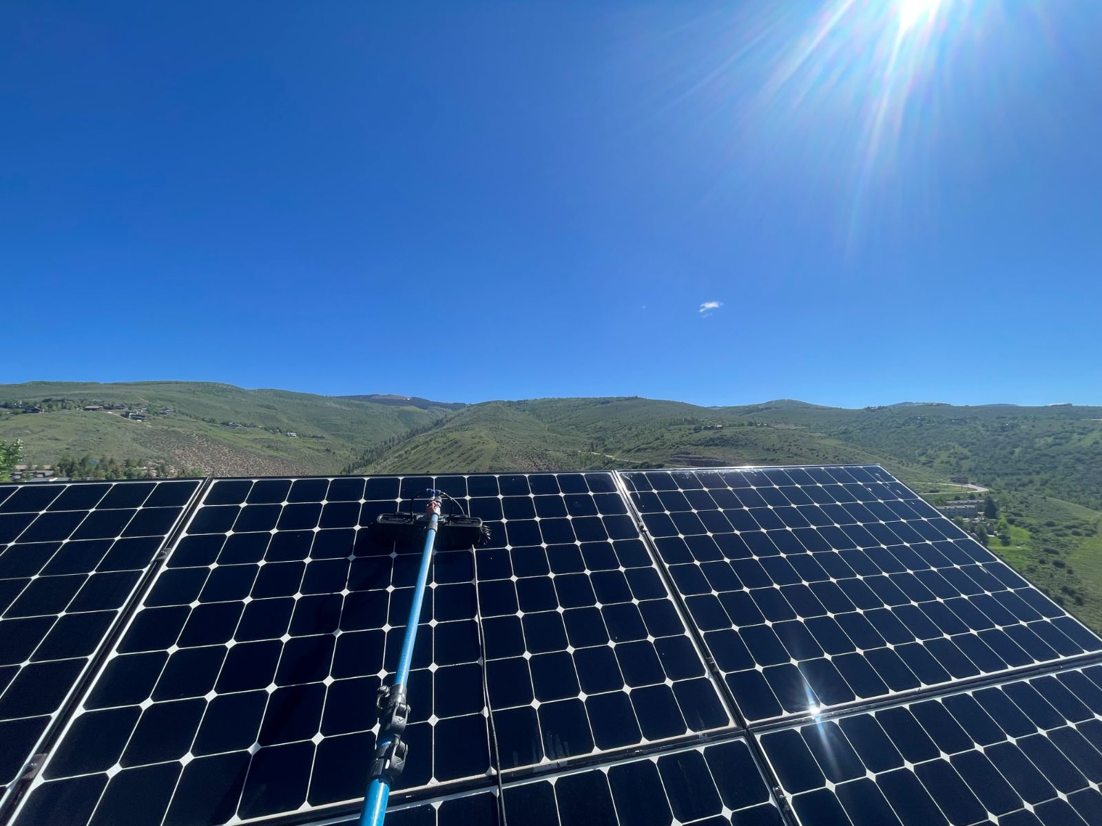 Solar panel array being cleaned under a blue sky