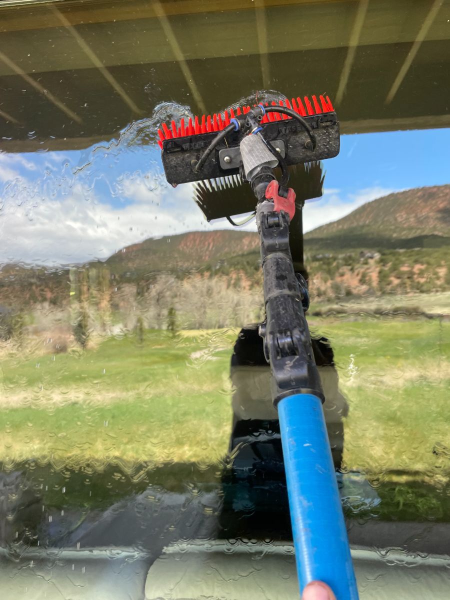Water-fed brush rinsing an upper window