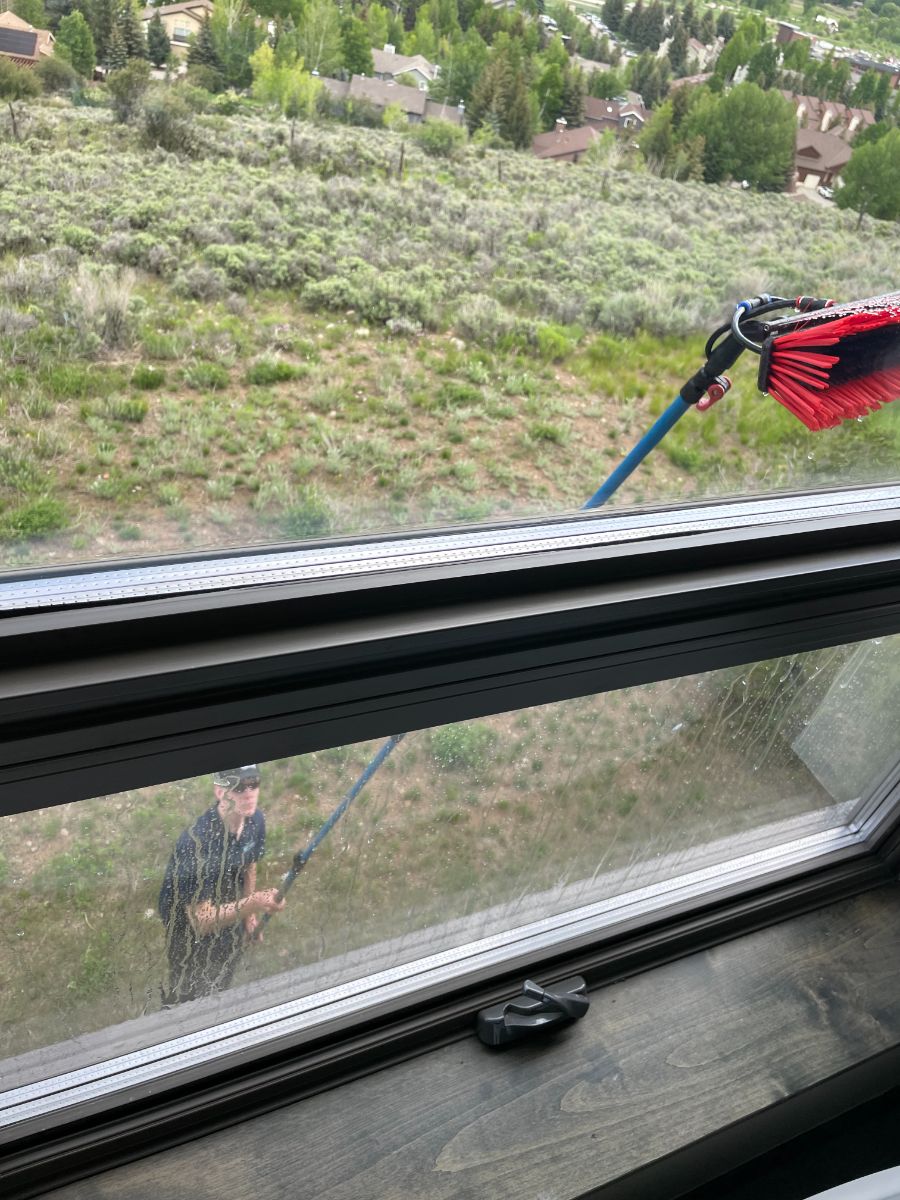 Brush scrubbing a window frame from outside